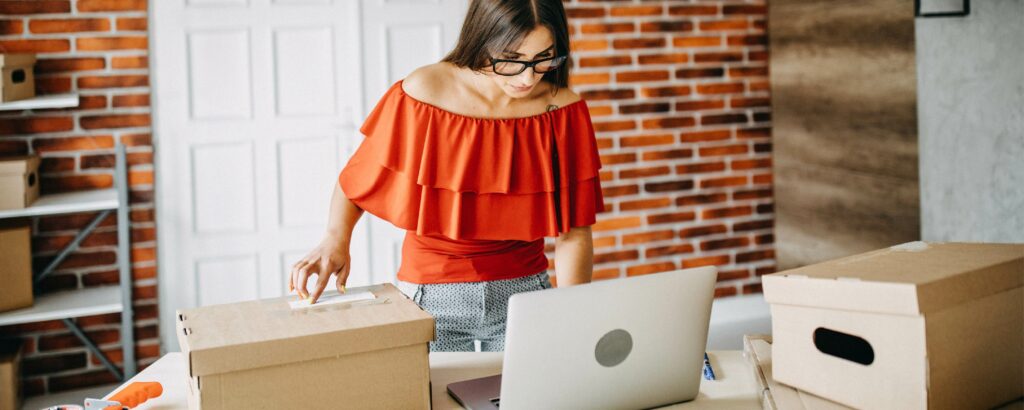 Someone packing online orders with an open laptop