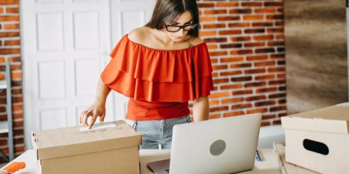 Someone packing online orders with an open laptop